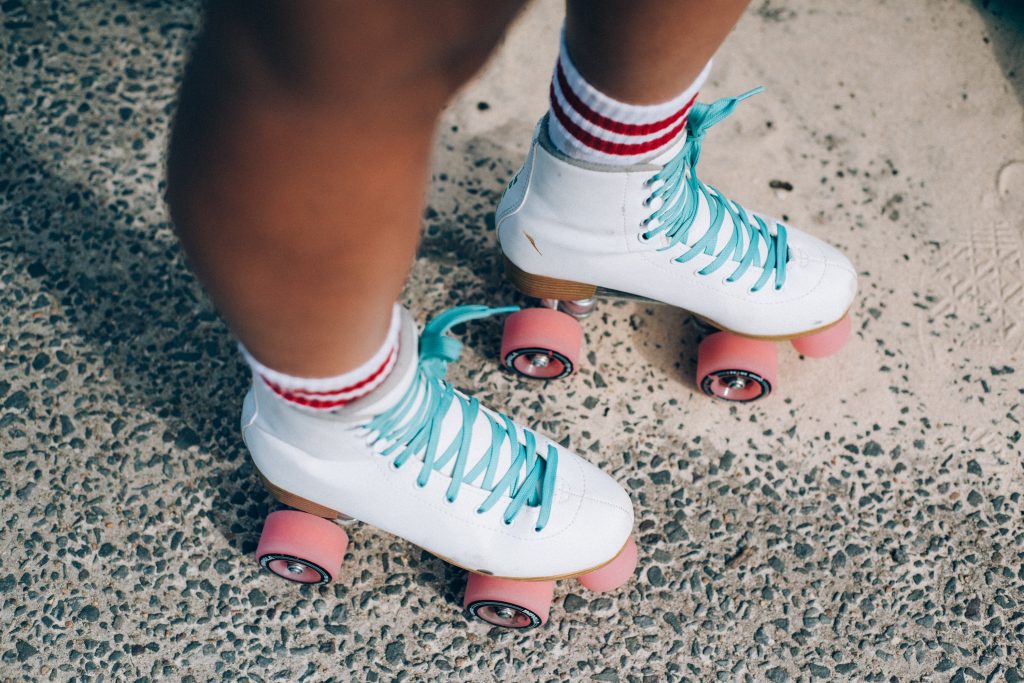 Knee down shot of girl wearing white skates with pink wheels