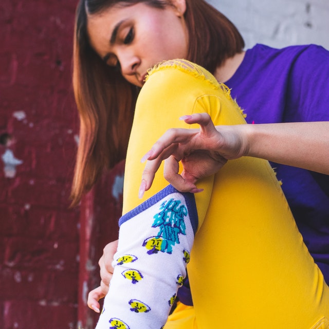 Woman in yellow pants putting on colorful socks