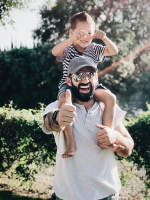 Father giving boy piggy back ride while giving thumbs up 