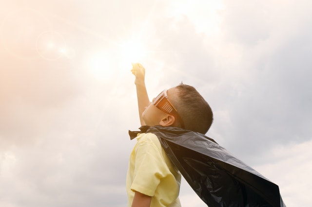 Kid with cape striking superhero pose