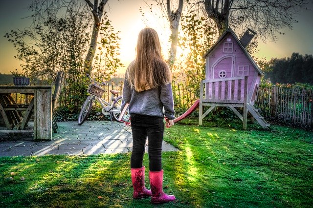 Girl standing in kid-friendly backyard at sunset