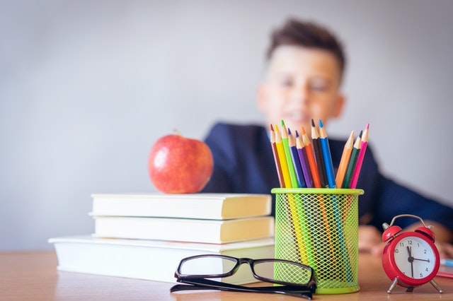 Kid sitting at desk with books and school supplies