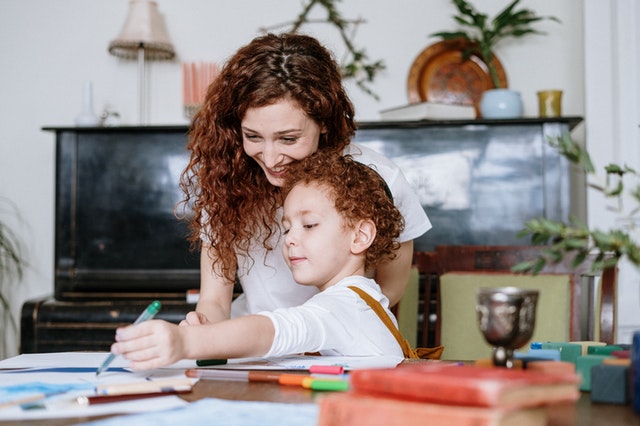 Mom helping child with homework at kitchen table