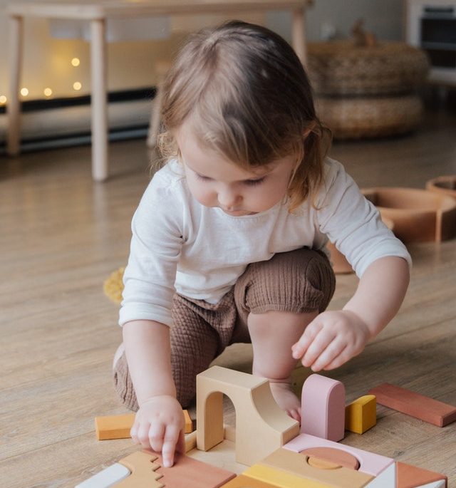 Little kid playing with wooden blocks