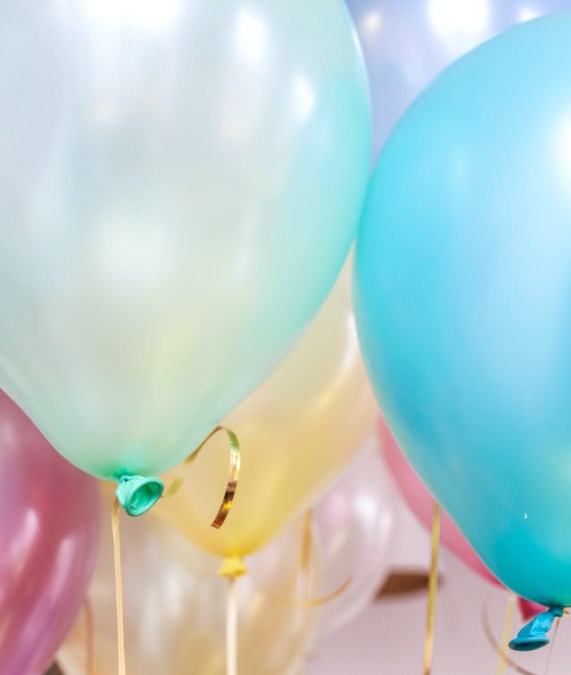 Close up of colorful pastel balloons with metallic ribbons