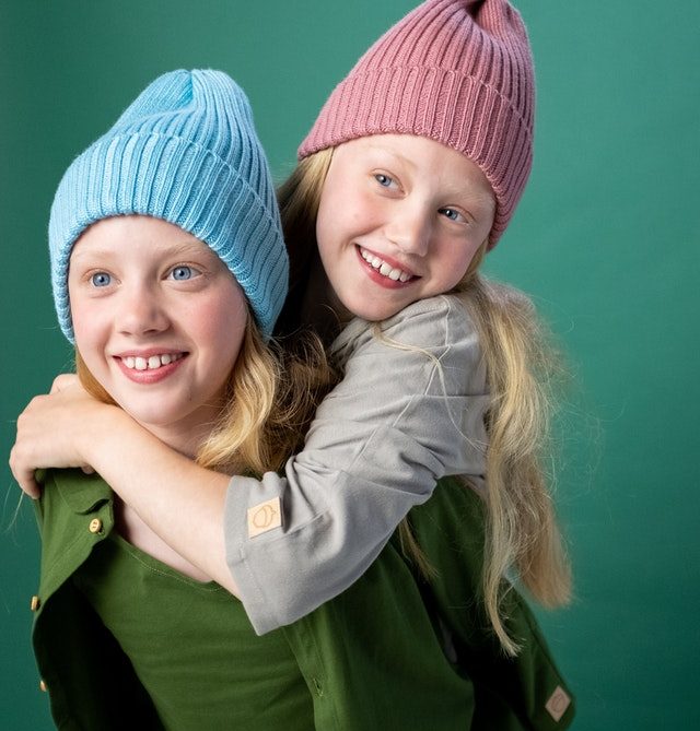 Twin girls in beanie hats giving piggyback ride