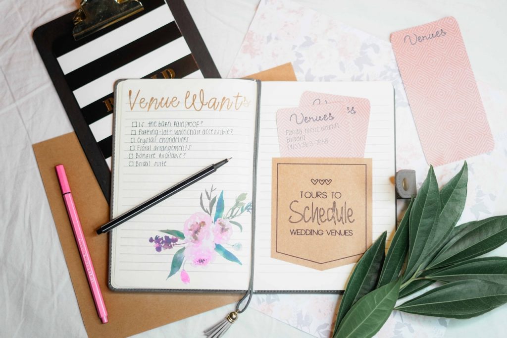 Event venue checklist in journal on desktop with trendy accessories