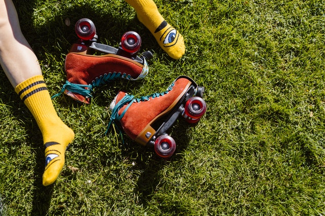 Legs in yellow socks on grass with bright orange roller skates